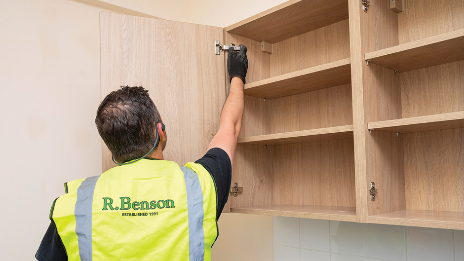R Benson employee checking hinges on kitchen unit