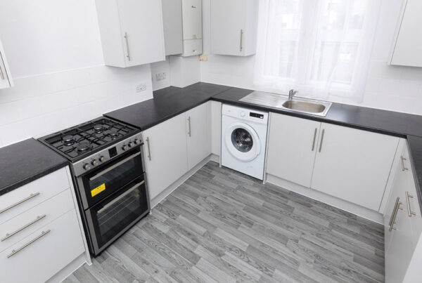 Picture of a refurbished kitchen with new white cupboards, black work surface and grey flooring